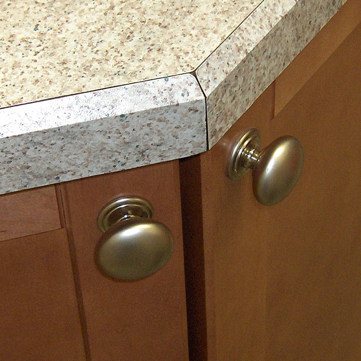 laminate countertop edge above a maple cabinet with brass knobs