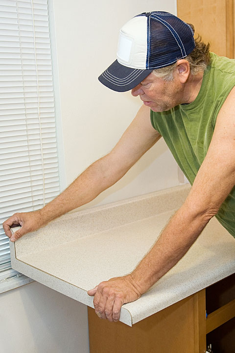 a carpenter installs a plastic laminate countertop